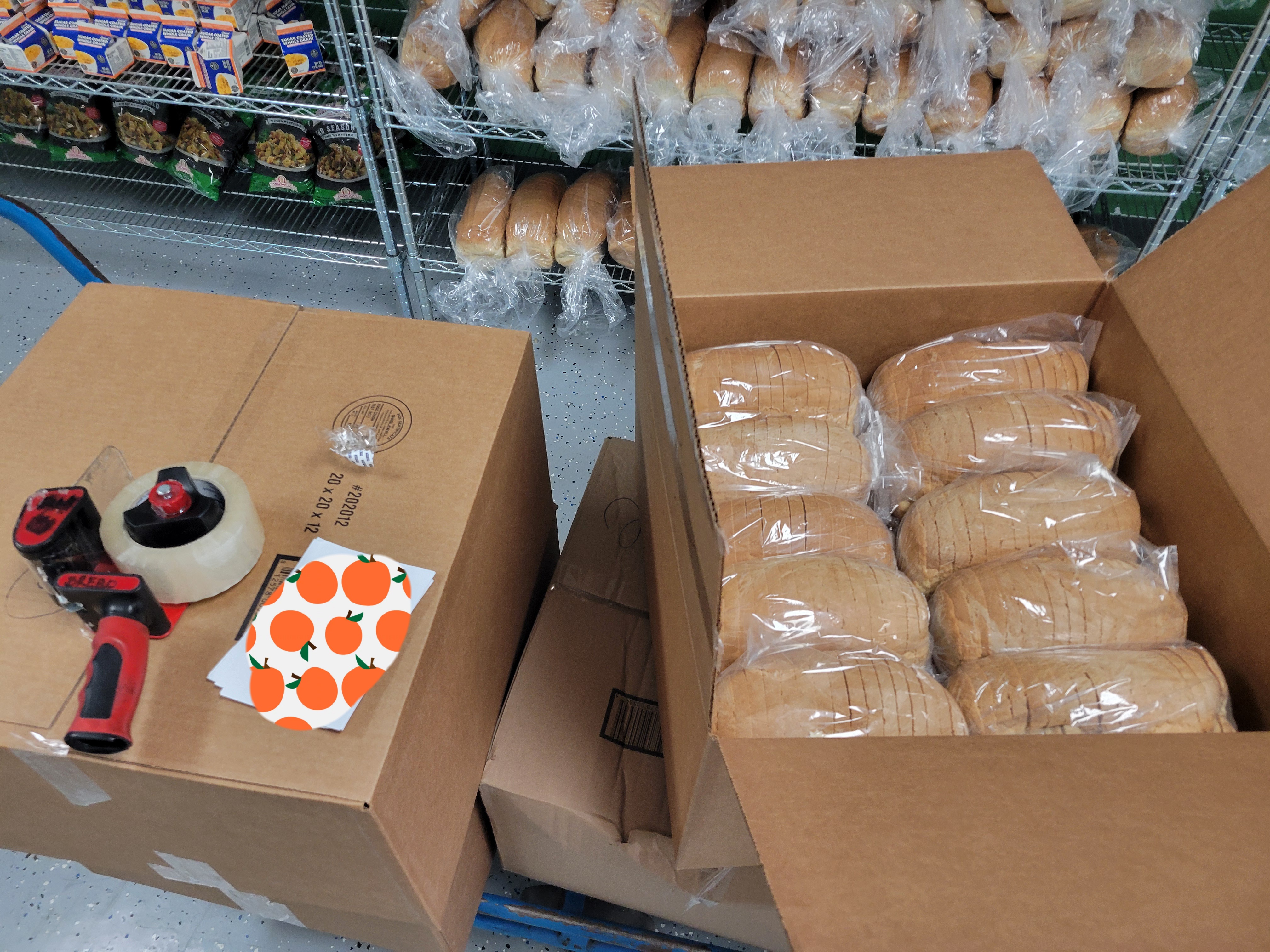 Cardboard box of breads with labels and tape gun on top of one.